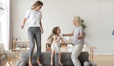 trzy pokolenia kobiet skaczące z radości na kanapie